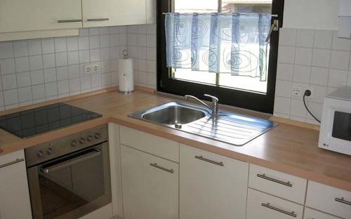 una cocina con fregadero y una ventana. en Ferienhaus Nr 6, Kategorie Königscard, Feriendorf Hochbergle, Allgäu, en Bichel