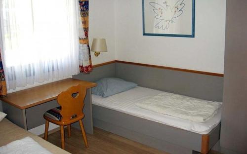 Habitación pequeña con cama pequeña y escritorio. en Ferienhaus Nr 6, Kategorie Königscard, Feriendorf Hochbergle, Allgäu, en Bichel