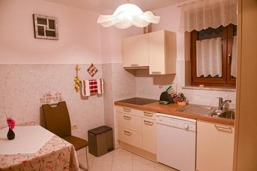- une cuisine avec des placards blancs, une table et un évier dans l'établissement Apartma PANORAMA, à Marezige