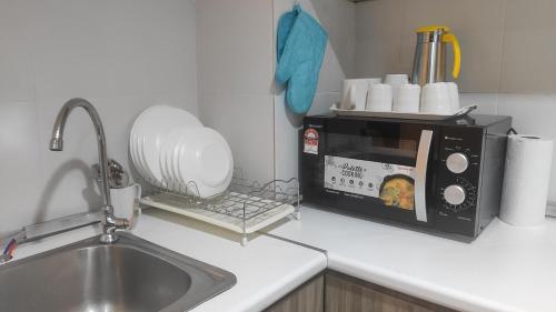 eine Küchentheke mit Spüle und Mikrowelle in der Unterkunft FRA Dreams @ Swiss Garden Resort Residences in Kuantan
