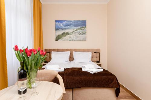 a bedroom with a bed and a table with flowers on it at Villa Nadzieja in Międzyzdroje