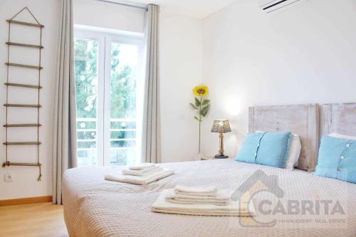 a bedroom with a bed with blue pillows and a window at Apartamento Girassol Cabanas Gardens by Your Home Algarve in Cabanas de Tavira