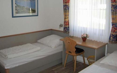 um pequeno quarto com uma cama e uma secretária com uma cadeira em Ferienhaus Nr 18, Kategorie Komfort, Feriendorf Hochbergle, Allgäu em Bichel