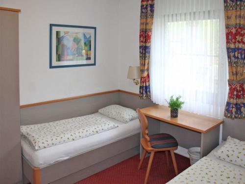 een kamer met 2 bedden, een bureau en een tafel bij Ferienhaus Nr 136, Kategorie Komfort Plus, Feriendorf Hochbergle, Allgäu in Karlsebene