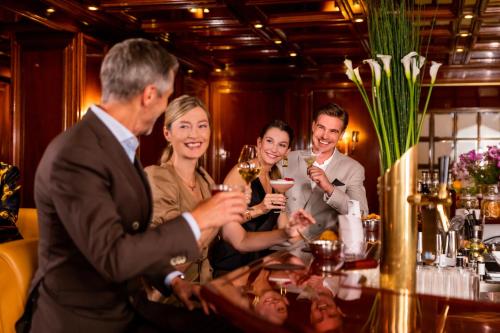 a group of people sitting around a bar holding drinks at Excelsior Hotel Ernst am Dom in Cologne
