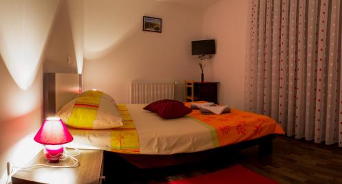 Guest House Buk Rastoke في سلوني: غرفة نوم بسرير وطاولة مع مصباح