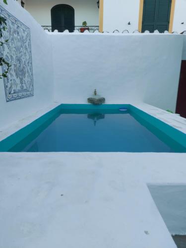 a swimming pool in a white wall with a blue pool at Casa do Páteo in Vila Nova da Baronia