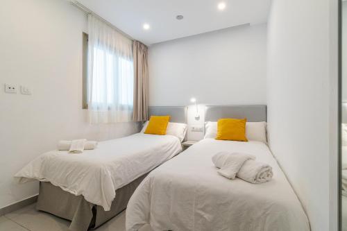two beds in a hospital room with yellow pillows at Modern Flat Las Canteras in Las Palmas de Gran Canaria