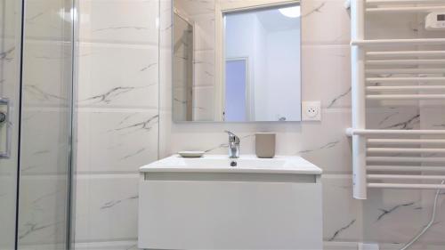 une salle de bain blanche avec un lavabo et un miroir dans l'établissement Delille centre ville 01, à Nice