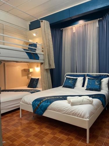 two bunk beds in a room with blue curtains at Acozyposhtel in Bangkok