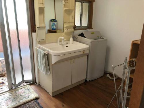 a bathroom with a sink and a washing machine at 吉野 古民家一棟貸しの体験型ゲストハウスKuraKura in Kami-ichi