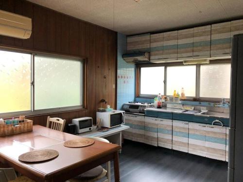 a kitchen with a table and a kitchen with windows at 吉野 古民家一棟貸しの体験型ゲストハウスKuraKura in Kami-ichi