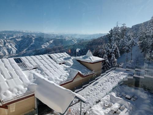 a resort covered in snow with mountains in the background at Radisson Kufri in Shimla