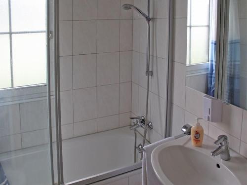 a white bathroom with a shower and a sink at Ferienhaus Nr 40, Kategorie Komfort L, Feriendorf Hochbergle, Allgäu in Bichel