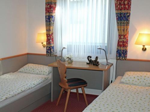 a bedroom with two beds and a desk with a chair at Ferienhaus Nr 123, Kategorie Komfort Plus L, Feriendorf Hochbergle, Allgäu in Karlsebene