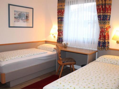 a room with two beds and a desk and a window at Ferienhaus Nr 28, Kategorie Königscard, Feriendorf Hochbergle, Allgäu in Bichel