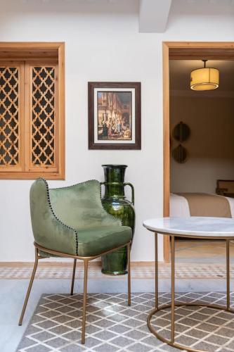 a living room with a green chair and a table at Riad Le Saadien ,Adult only in Marrakech