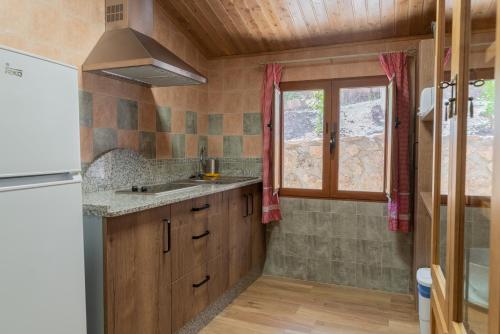 cocina con armarios de madera, fregadero y ventana en Casas rurales El Arbol de la Vida en Riópar