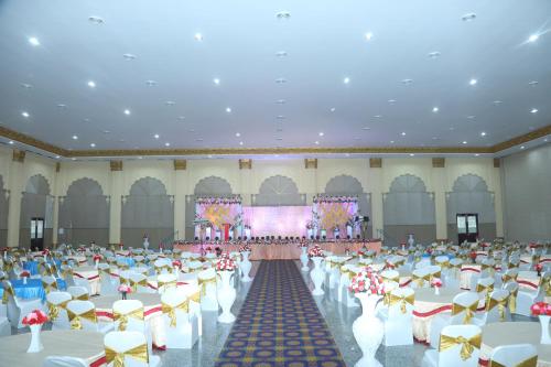 a large banquet hall with white tables and chairs at Gadiraju Palace Convention Centre & Hotel in Visakhapatnam