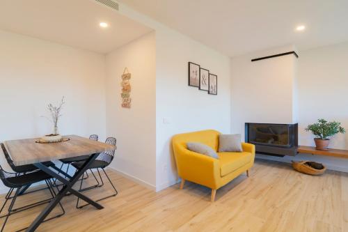 a living room with a table and a yellow chair at Alojamiento MAS EL CASTELL DEL BRULL in El Brull