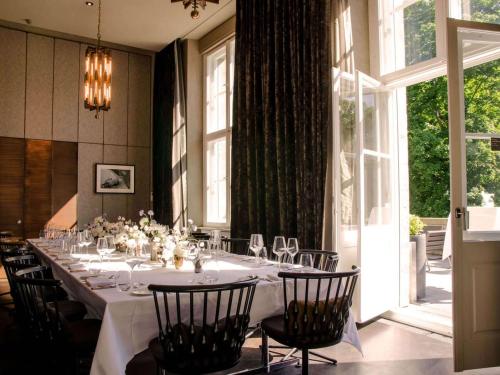 a dining room with a long table with chairs at SO/ Berlin Das Stue in Berlin