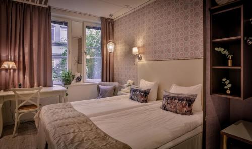 a bedroom with a bed and a desk and a window at Freys Hotel in Stockholm