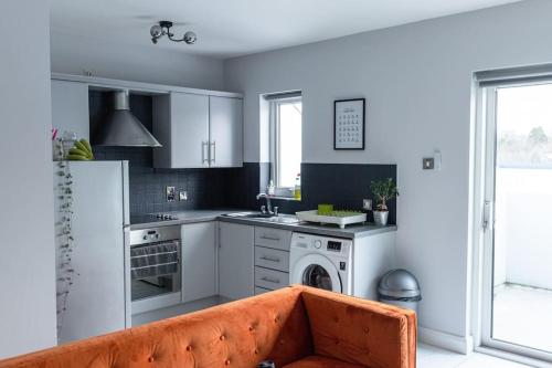 a kitchen with white cabinets and an orange couch at Causeway Coast Sea Front apartment - Ballycastle in Ballycastle