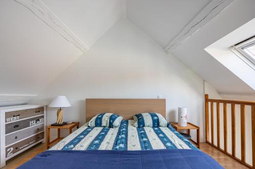 a bedroom with a bed with a blue comforter at Maison L'Hippocampe in Saint-Aubin-sur-Mer