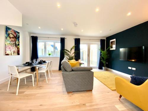 a living room with a table and a dining room at Stunning NEW Large 3 bedroom House - 5 Minutes to the nearest Beach! - Great Location - Garden - Parking - Fast WiFi - Smart TV - Newly decorated - sleeps up to 7! Close to Poole & Bournemouth & Sandbanks in Lytchett Minster
