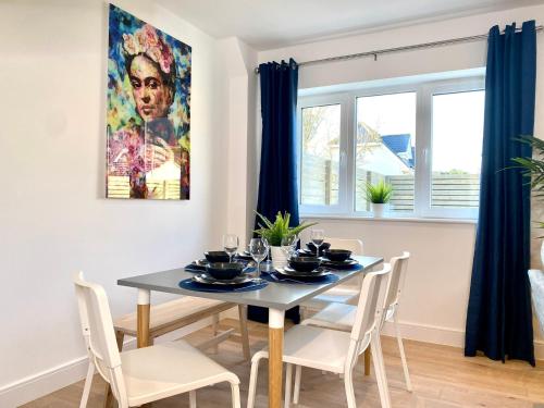 a dining room with a table and chairs and a painting at Stunning NEW Large 3 bedroom House - 5 Minutes to the nearest Beach! - Great Location - Garden - Parking - Fast WiFi - Smart TV - Newly decorated - sleeps up to 7! Close to Poole & Bournemouth & Sandbanks in Lytchett Minster
