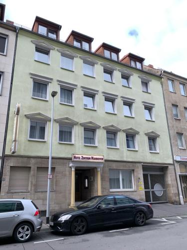 a building with two cars parked in front of it at Hotel Zentrum in Hannover