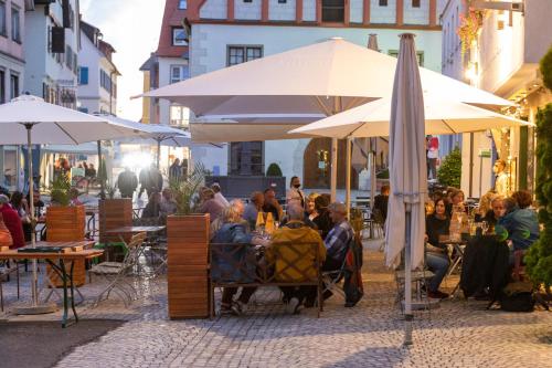 a group of people sitting at tables under umbrellas at Hotel Restaurant Grüner Baum und Altes Tor in Bad Waldsee
