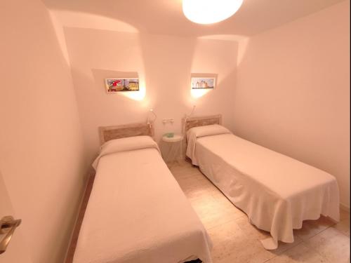 Habitación pequeña con 2 camas y paredes blancas. en Piso aubi, en Sant Antoni de Calonge
