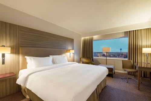 a hotel room with a large bed and a window at Radisson Blu Manchester Airport in Hale