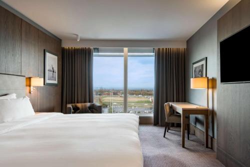 a hotel room with a bed and a desk and a window at Radisson Blu Manchester Airport in Hale