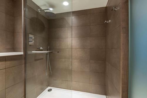 a bathroom with a shower with a glass door at Radisson Blu Manchester Airport in Hale