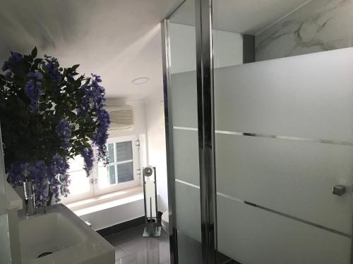 a bathroom with a shower and a vase of purple flowers at O Pátio in Fernao Ferro