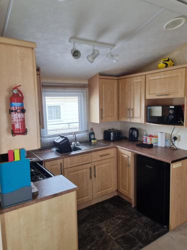 a kitchen with wooden cabinets and a black dishwasher at 3 Bedroom Sleeps 6 on Coral Beach in Ingoldmells