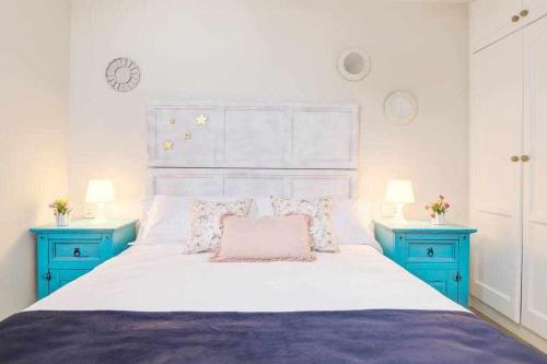 1 dormitorio con 1 cama blanca grande y mesitas de noche azules en La Favorita preciosa villa con piscina privada, en Corralejo