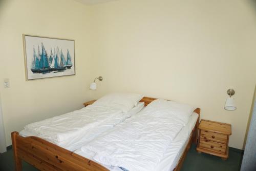 1 cama con sábanas blancas y una foto en la pared en Villa Seepferdchen Wohnung 01, en Kühlungsborn