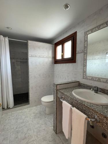 a bathroom with a sink and a toilet and a mirror at Hostal CAN GALLU in Cala Ratjada
