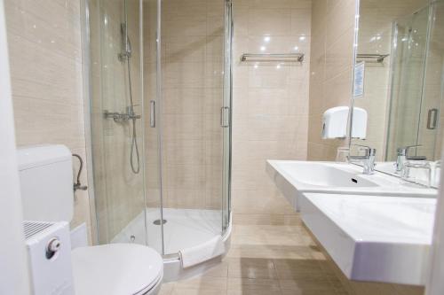 a bathroom with a toilet and a sink and a shower at Hotel Árpád in Tatabánya