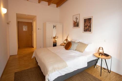 a bedroom with a large white bed and a table at Hotel Hofgut Imsbach Lapointe in Tholey