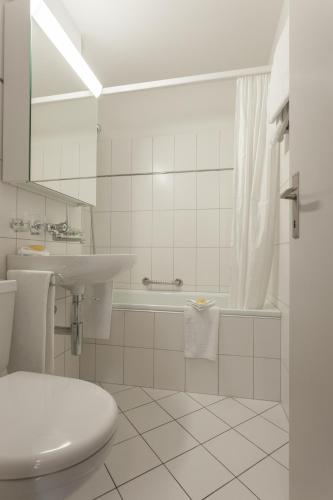 a bathroom with a sink and a tub and a toilet at EMA House Serviced Apartments Aussersihl in Zürich