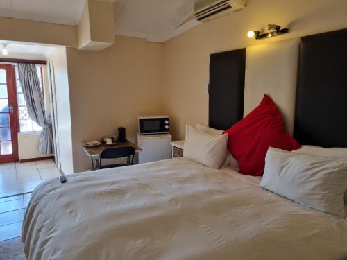 a bedroom with a large white bed with red pillows at Mthatha Rest 2 in Mthatha