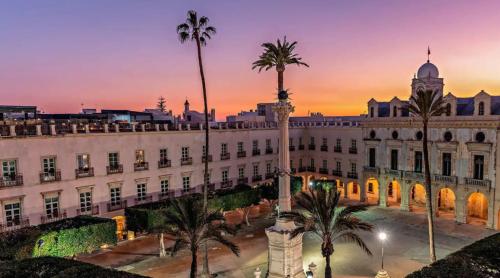 Expoholidays-Apartamentos Almería Centro PARKING gratis في ألميريا: مبنى كبير أمامه أشجار نخيل