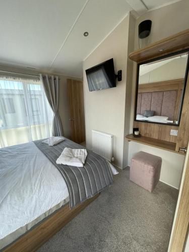 a bedroom with a large bed and a mirror at Seton sands holiday park - Premium caravan - 2 bedroom sleeps 4 in Port Seton