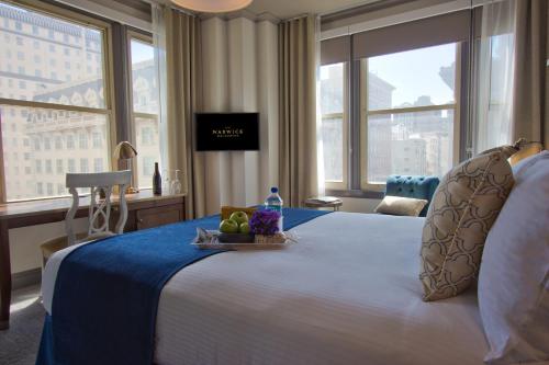 a hotel room with a bed with a tray of fruit on it at Warwick San Francisco in San Francisco