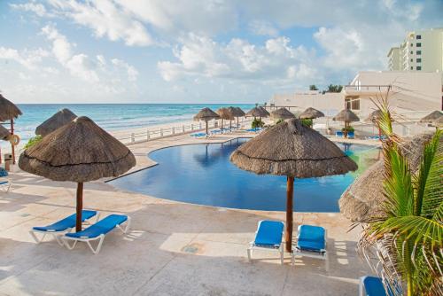 a swimming pool with chairs and umbrellas and the ocean at Perfect vacation getaway,Ocean View,Wifi, Beach in Cancún