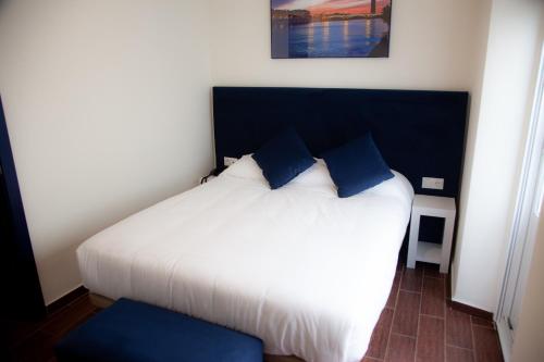 a bedroom with a white bed with blue pillows at Noches en Triana in Seville